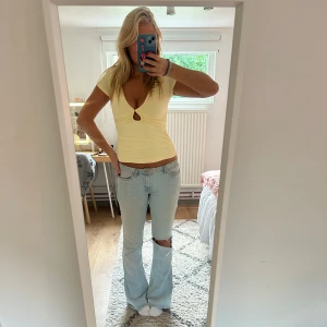 Gul topp - Snygg ljusgul croppad topp med djup v-ringning och liten cut-out framtill. Topp med korta ärmar och figurnära passform, perfekt till jeans eller kjol. Mjuk och stretchig i materialet, superfräsch till sommaren.