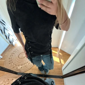 Svart t-shirt med snörning i sidorna - Cool svart t-shirt med tvättad look och snörningsdetaljer längs båda sidorna. Sparsamt använd! 