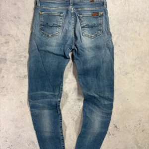 Ljusblå skinny jeans från 7 For All Mankind - Snygga ljusblå skinny jeans från 7 For All Mankind med klassisk femficksdesign och broderade bakfickor. Jeansen har en något tvättad look och gylf med dragkedja. Perfekta för dig som gillar en smal passform och stilren denim.