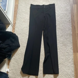 Svarta wide kostymbyxor från Nelly - Snygga svarta kostymbyxor från Nelly i storlek 34. Byxorna har en klassisk wide passform med låg midja och raka ben samt lite utsvängda ben