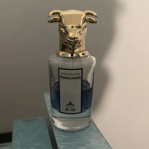 Penhaligon's Portraits Mr Sam  - Exklusiv parfymflaska från Penhaligon's Portraits-serie, Mr Sam. Flaskan är genomskinlig med blå vätska och har ett unikt guldfärgat lock i form av ett djurhuvud. Lyxig och iögonfallande design som sticker ut i parfymhyllan. 75ml flaska 50% kvar.