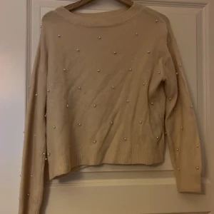 Beige tröja med pärlor från H&M - Superfin beige tröja från H&M i storlek XS. Tröjan har långa ärmar och är dekorerad med små pärlor över hela framsidan och på ärmarna. Mjuk och skön, perfekt för att lyfta en enkel outfit.