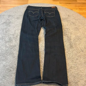Levi's 517 mörkblå jeans - Mörkblå Levi's 517 jeans med klassiska kontrastsömmar och bootcut passform. Jeansen har fem fickor, dragkedja och knapp i midjan samt det ikoniska Levi's-märket på bakfickan. Perfekta för dig som gillar en tidlös och avslappnad stil.