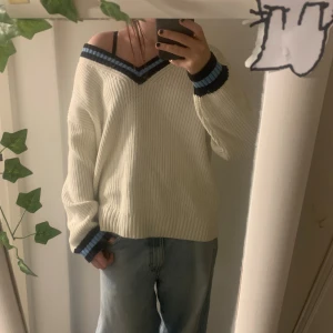 Vit stickad offshoulder tröja y2k baggy opium - Vit stickad tröja med oversized passform och offshoulder-design. V-ringad hals med svarta och blå ränder samt matchande muddar. Perfekt för dig som gillar en chill och trendig stil. Tjockt ribbstickat material som känns både mysigt och snyggt. Lappen säger S men känns mer som M/L. Bra skick, lite nopprig på vissa ställen, skriv privat för mer bilder 