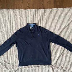 Marinblå half zip från Polo Ralph Lauren - Säljer en marinblå långärmad tröja från Polo Ralph Lauren med half zip, blå längst insidan av kragen. Storleken står L men passar M.
