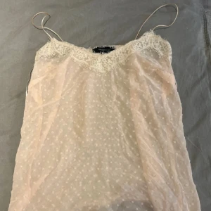 Vintage spets linne - Supersött ljusrosa linne från Atmosphere med tunna axelband och spetsdetaljer vid halsringningen. Prickigt mönster i tyget och transparent känsla som ger en romantisk vibe. Perfekt för dig som gillar feminina och trendiga toppar.