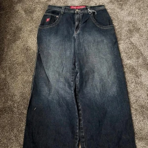 Bästa JNCO-jeans till överkomliga priser - Säljer ett par mörkblå JNCO jeans med riktigt bred passform och en stor broderad snake på bakfickan. Klassisk femficksmodell med röda JNCO-detaljer och cool streetkänsla. Perfekta för dig som gillar baggy stil och vill sticka ut.