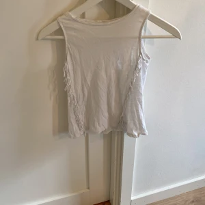 Vit ärmlös linnetopp från MNG Kids - En enkel och stilren vit linnetopp från MNG Kids. Toppen är ärmlös och har en rak passform, perfekt för varma dagar. Tillverkad i mjuk bomull som känns skön mot huden. Passar till både jeans och shorts.