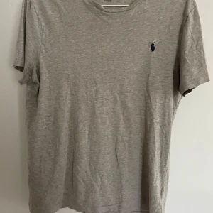 Grå t-shirt från Polo Ralph Lauren - Snygg grå t-shirt från Polo Ralph Lauren i mjuk bomull. Skick 8-10. Bra storlek fast passar mest de som har S skulle jag säga