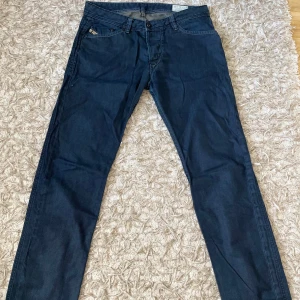 Diesel Darron raka jeans blå - Säljer ett par klassiska blå jeans från Diesel, modell Darron. De har raka ben, normal passform och snygga detaljer med kontrastsömmar. Jeansen är tillverkade i slitstarkt denim och har fem fickor samt läderpatch bak i midjan.