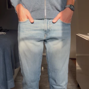 Ljusblå jeans från Polo Ralph Lauren - Säljer ett par ljusblå jeans från Polo Ralph Lauren i klassisk straight fit. Jeansen har fem fickor, normal passform och är tillverkade i mjuk bomullsdenim. Perfekta för dig som gillar en avslappnad och tidlös look. Storlek 31/32. Jeansen har slitnigar men inget som defekt utan design.