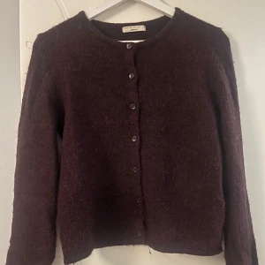 Vinröd stickad kofta från Gina Tricot - Mysig vinröd kofta från Gina Tricot i stickat material. Koftan har rund halsringning, långa ärmar och knäppning med knappar. Den ser lite brun ut på bilderna men är vinröd!💕