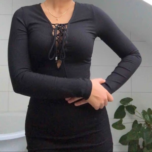  - En svart festklänning som är figursydd och funkar för både XS och S! Den har knytningar vid bröstet och går ner till strax över knäna. 