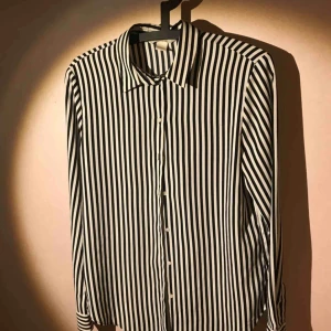  - Svartvit randig blus, polyester med silkeskänsla, rak 90-tals modell med smal krage, två knappar i manchetten