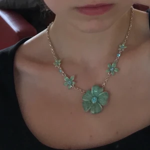 Halsband med blomma - Jättefint halsband med glittriga blommor och blå stenar! Går att göra hur långt/kort man själv vill ha det. Frakt 11kr