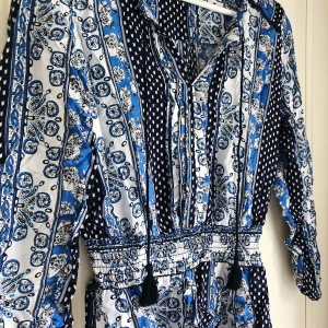Blå blus från H&M - Blus med mönster i blått och markering i midjan från H&M. Storlek 34. Använd endast vid provningstillfället.