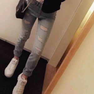  - Ett par ljusblå jeans med slitningar. De är mycket stretchiga och har använts två gånger då jag inte är något fan när de kommer till jeans. De är högmidjade med bakfickor. 