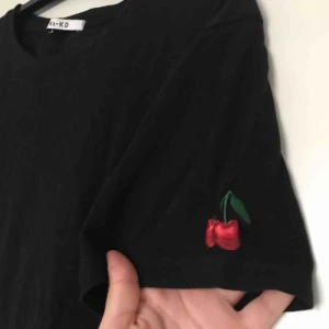  - Kortare t-shirt från NA-KD med körsbärsbrodering på ena armen 