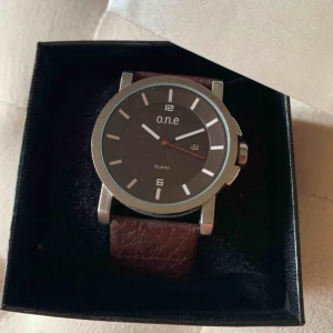  - Klocka från märket o.n.e med brunt läderband till. Ask medföljer, säljes pga används ej.
