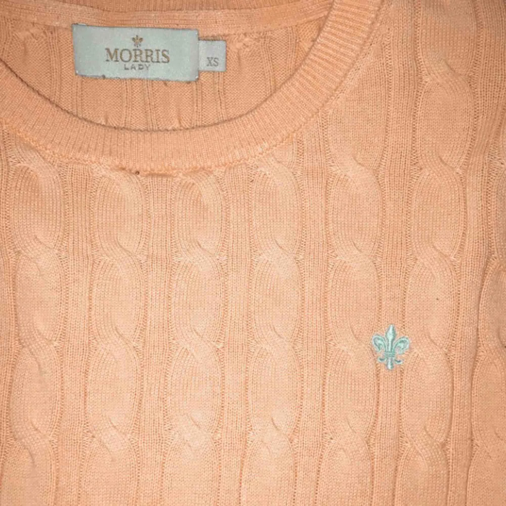 Korallrosa tröja med ljusblått inbroderat tryck från Morris. Nypris 1200kr. Stickat.
