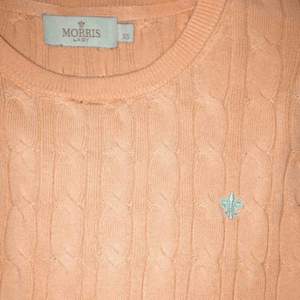 Korallrosa tröja med ljusblått inbroderat tryck från Morris. Nypris 1200kr