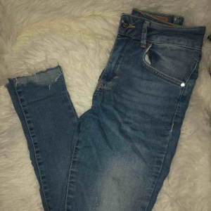  - Blåa jeans med slitningar på knäna, ena låret och längst ned vid ankeln!! Hög midja💙