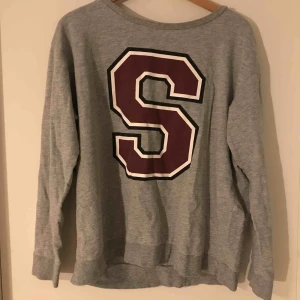  - Har aldrig använt den, då den är för stor för mig. Tröjan är ljus grå med ett vinrött S med vita och svarta konturer. Kan mötas upp i Stockholm annars betalar kunden för frakt.