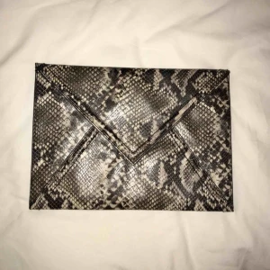  - Ormskinnsmönstrad kuvertväska från H&M. Endast använd ett fåtal tillfällen, i nyskick. Fuskskinn.