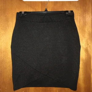  - Kjol i glittrigt material. Omlott/korsad framtill och elastisk i midjan. Använd 1 gång. 