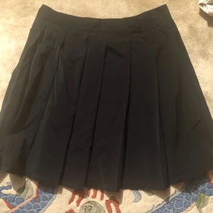  - Svart plisserad kjol med dragkedja i sidan