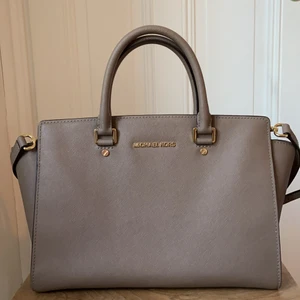 Michel Kors väska - Säljer en jättefin Michael Kors väska i gott skick, ser knappt använd ut. Men med tanke på två små fläckar av genomskinligt nagellack i botten på väska så är priset lägre. Modell: Selma, Orginalpris: 3400kr. Frakt tillkommer 🙌🏼