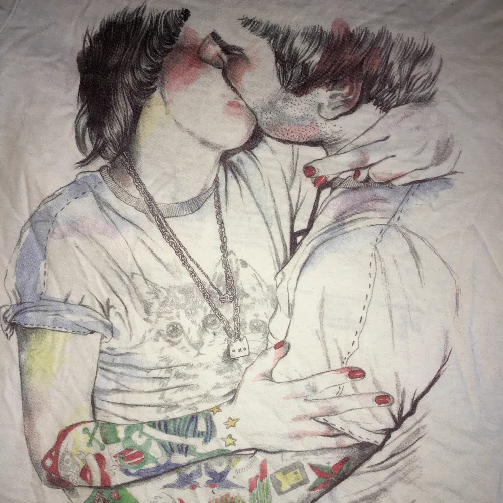 En skön secondhand vit T-shirt från T-POST med design som förseställer två personer som kysser varandra, om man vänder ut och in på t-shirten så står det lite om inspirationen till designen och om designern Esra Røise. Uppskattad storlek är S, Frakt 22 kr. T-shirts.
