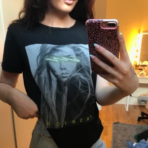 T-shirt - Svart t-shirt med ett grått tryck + lite neon       Står ”L” men passar mig som har storlek XS/S