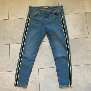 Blå jeans från Zara med gul/svarta detal - Blåa jeans från Zara med gul/svart detalj. Använda ett fåtal gånger. Frakt ingår 