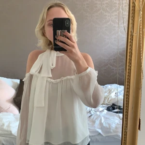 Blus från Zara - Superfin blus från Zara i storlek XS. Öppen kring axlarna bak och fram samt knyt kring halsen. Perfekt till sommaren, har en romantisk touch🥰 Blusen är i bra skick, finns någon sminkfläck men endast på insidan av kragen så det är inget som syns. + frakt