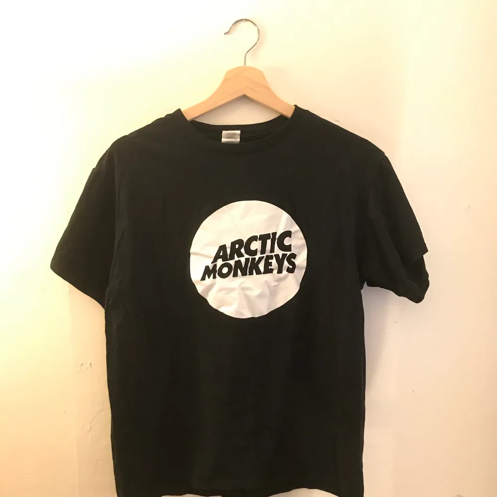 Svart t shirt med tryck av bandet arctic monkeys, bra band, den sägs vara i storlek L men passar mer likt en small/medium. T-shirts.