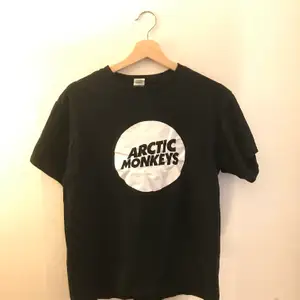 Svart t shirt med tryck av bandet arctic monkeys, bra band, den sägs vara i storlek L men passar mer likt en small/medium
