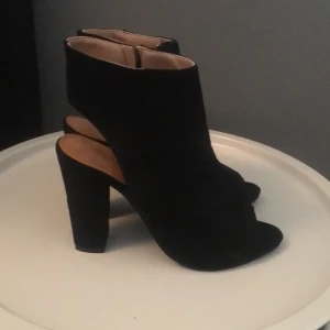 Svarta klackskor  - Oanvända klackar. Dragkedja på insidan. Strl 41 men små i storleken så passar mer en storlek 39/40. Skickas, frakt tillkommer. 