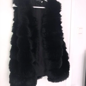 Pälsväst svart S/M - ⚡️ En väst i pälsliknande material, helsvart.   ⚡️ Bra skick!   ⚡️ Tryck på knappen under bilden för att köpa.   ⚡️ Kan skickas mot fraktkostnad. 
