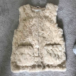  - En fuskpäls väst från zara. Den är i barnstorlek men sitter väldigt bra som en vuxen S. Den är jätteskön med två fickor framtill. Kan mötas upp i stockholm eller frakta (köparen står för frakt)
