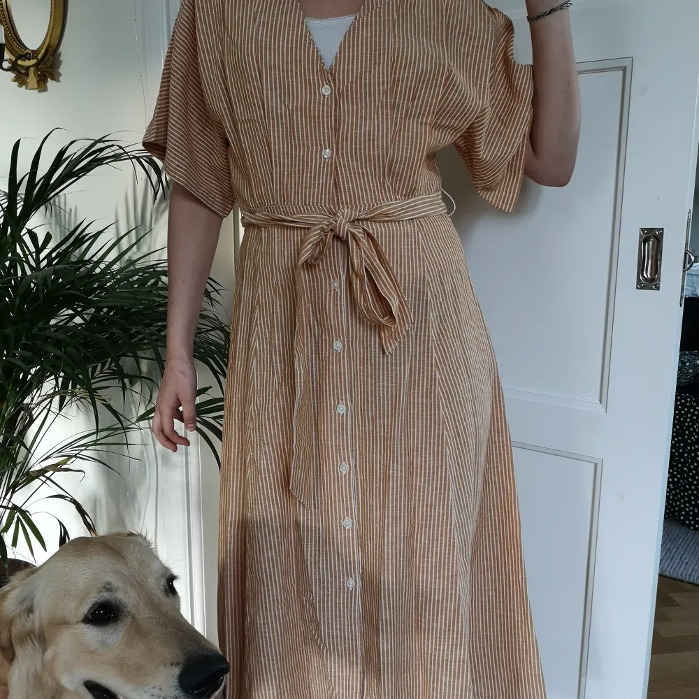 Fin senapsgul randig sommarklänning med knytband och knappar. Fin till fest med klackar eller till vardags med sneakers. Modellen 173 cm. Frakt står köparen för. . Mekot.