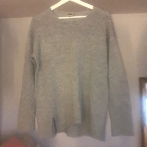 Grå stickad tröja  - En grå stickad tröja med slitsar på sidorna. 