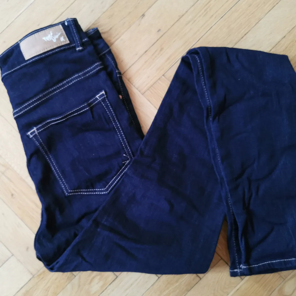 Mörkblå skitsnygga jeans av märket Never Denim köpta på BikBok. Hög midja. Aldrig använda då de är för små för mig. Storlek 26/33. Jeans & Byxor.