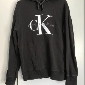 CALVIN KLEIN hoodie storlek medium (unisex) - Väl använd Calvin Klein hoodie i grå/brun/ljus svart nyans i storlek medium. Passar för både kvinnor och män. Köparen får stå för frakten 