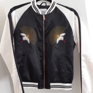 Bomberjacka - Sval bomber i silkigt material från Lager157. Perfekt nu till sommaren🌼 Dragkedja i kopparfärg!💎Fint skick💎 Samma svartvita detaljer i ärmsluten som i kragen. Frakt: 59:- Postens M-emballage.