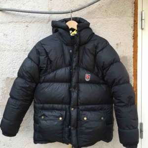  - Dunjacka från fjällräven i mycket bra skick.  Lite skrynklig då den legat på vinden. Färg: svart. Storlek: xxxs. Nypris 5999kr.  Det finns tre pyttesmå hål på jackan som är knappt synbara. Frakt 140kr