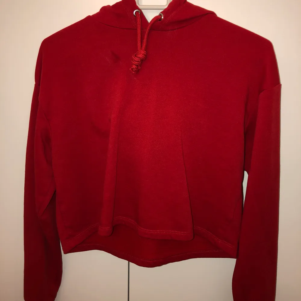 En röd croppad tröja från H&M, har använts 1 gång. Har även en luva där bak. Storlek XS men passar även S. Ordinarie pris: 100 kr. Tröjor & Koftor.