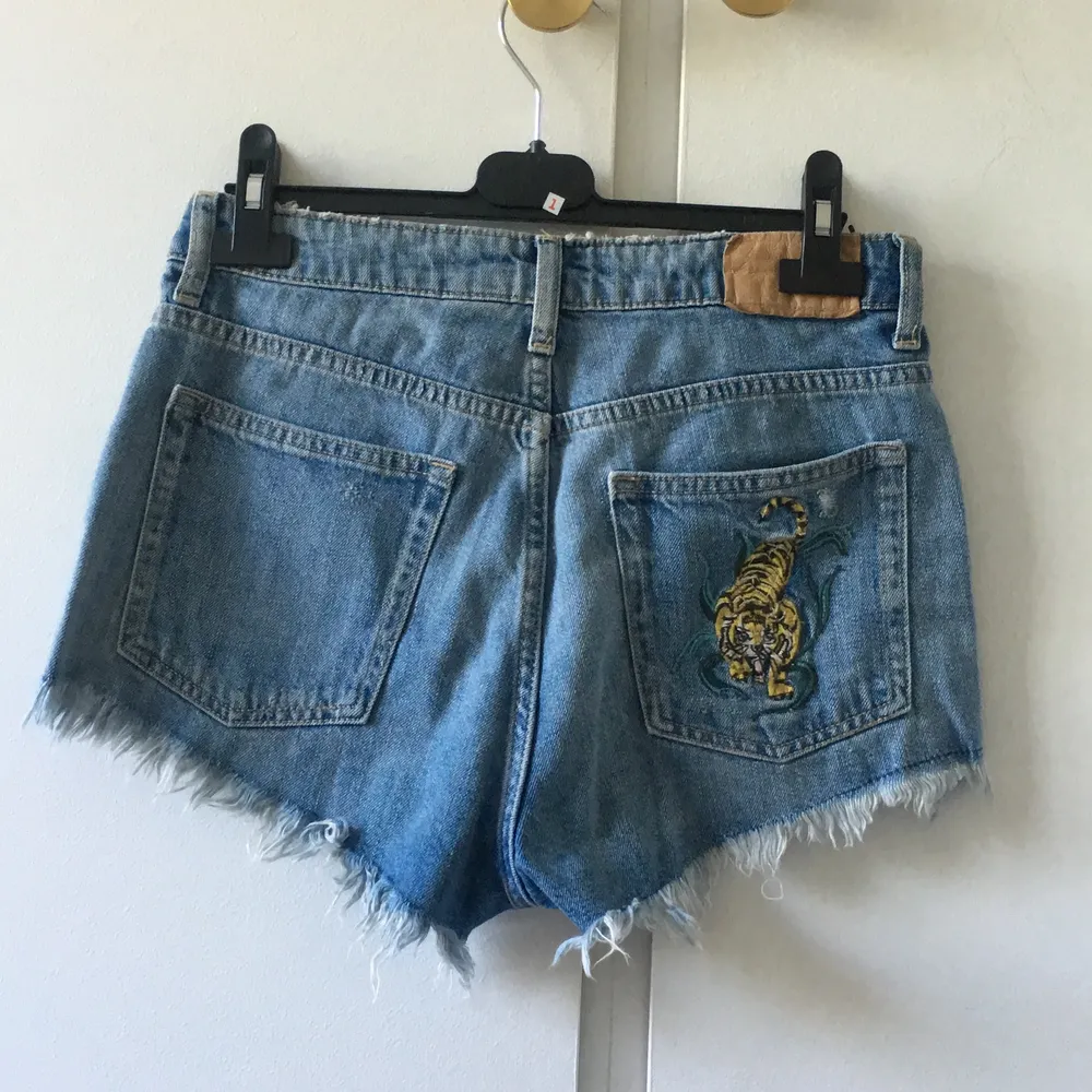 Blåa shorts med slitning längst ner. Detaljer på ena bakfickan och under ena framfickan. Frakten ingår i priset!💖. Shorts.