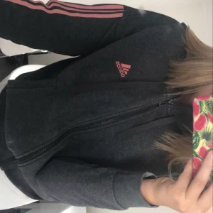 mörkgrå kofta - mörkgrå kofta från adidas med rosa sträck ! den har en luva och är jätte skön , säljer för 100 kr + frakt , storlek s