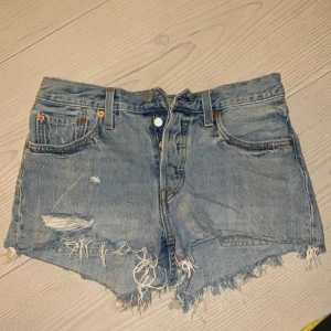 Ripped Levis shorts - Högmidjade Korta ripped Jeans short som blivit lite missfärgade vid etiketten efter jag tvättade dom men det syns inte så mycket. Använt bara nån gång, dom har knappar istället för dragkedja